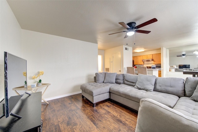 living room featuring a textured ceiling, dark wood-type flooring, and ceiling fan