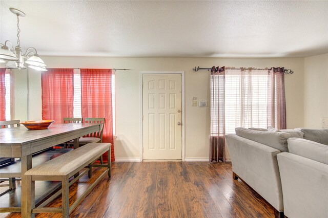 dining space with a textured ceiling, a notable chandelier, and dark hardwood / wood-style flooring