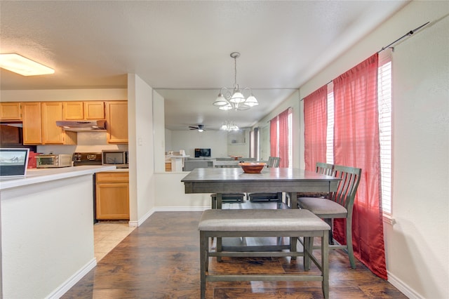 dining space with ceiling fan with notable chandelier and light hardwood / wood-style flooring