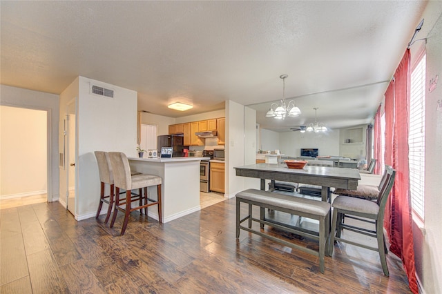 dining room with hardwood / wood-style floors, an inviting chandelier, and a textured ceiling