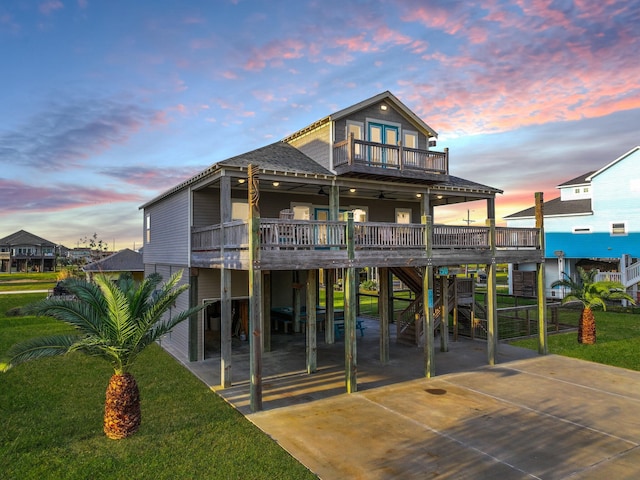 2025 Vista Dr, Crystal Beach, TX 77650 - back of house at dusk featuring a balcony, a carport, a yard, and ceiling fan