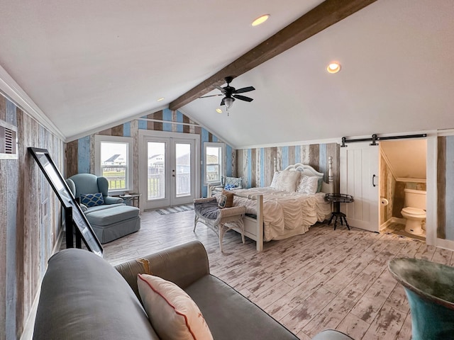 bedroom with ceiling fan, light hardwood / wood-style flooring, vaulted ceiling with beams, a barn door, and connected bathroom