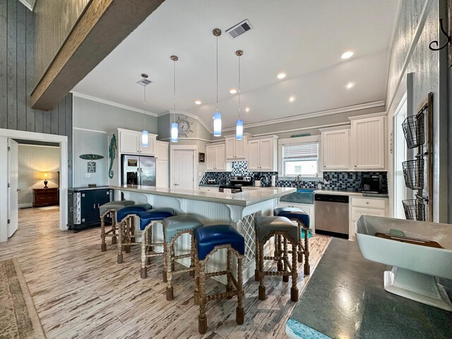 kitchen featuring light hardwood / wood-style floors, hanging light fixtures, a kitchen island, appliances with stainless steel finishes, and backsplash