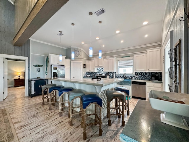 2025 Vista Dr, Crystal Beach, TX 77650 - kitchen featuring appliances with stainless steel finishes, backsplash, light wood-type flooring, white cabinetry, and crown molding