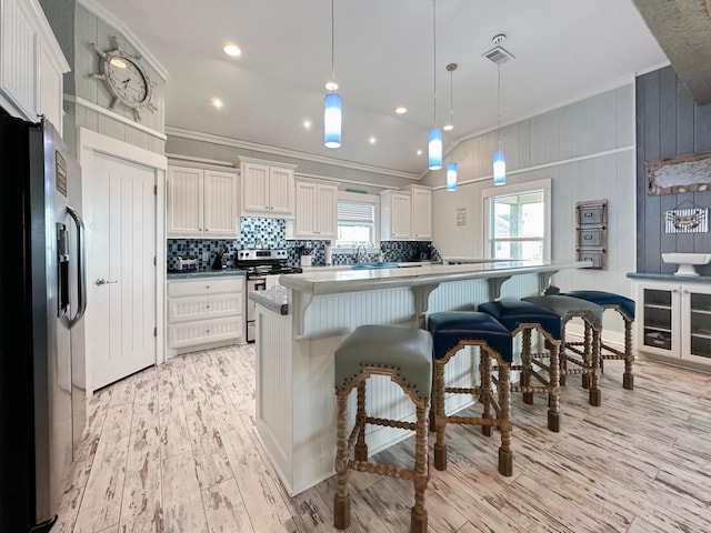 2025 Vista Dr, Crystal Beach, TX 77650 - kitchen with stainless steel appliances, ornamental molding, white cabinets, light wood finished floors, and tasteful backsplash