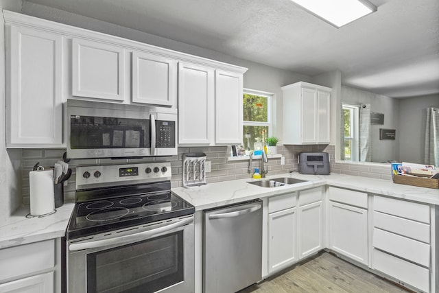 kitchen with stainless steel appliances, white cabinetry, tasteful backsplash, and sink