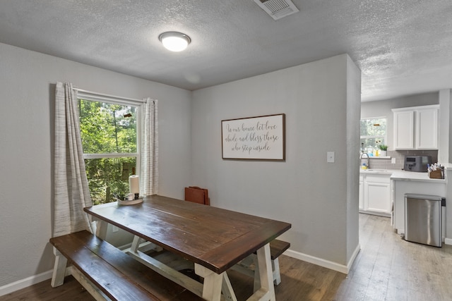 dining space with sink, a textured ceiling, and light wood-type flooring