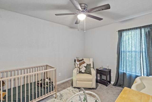 bedroom featuring ceiling fan, a nursery area, and light carpet