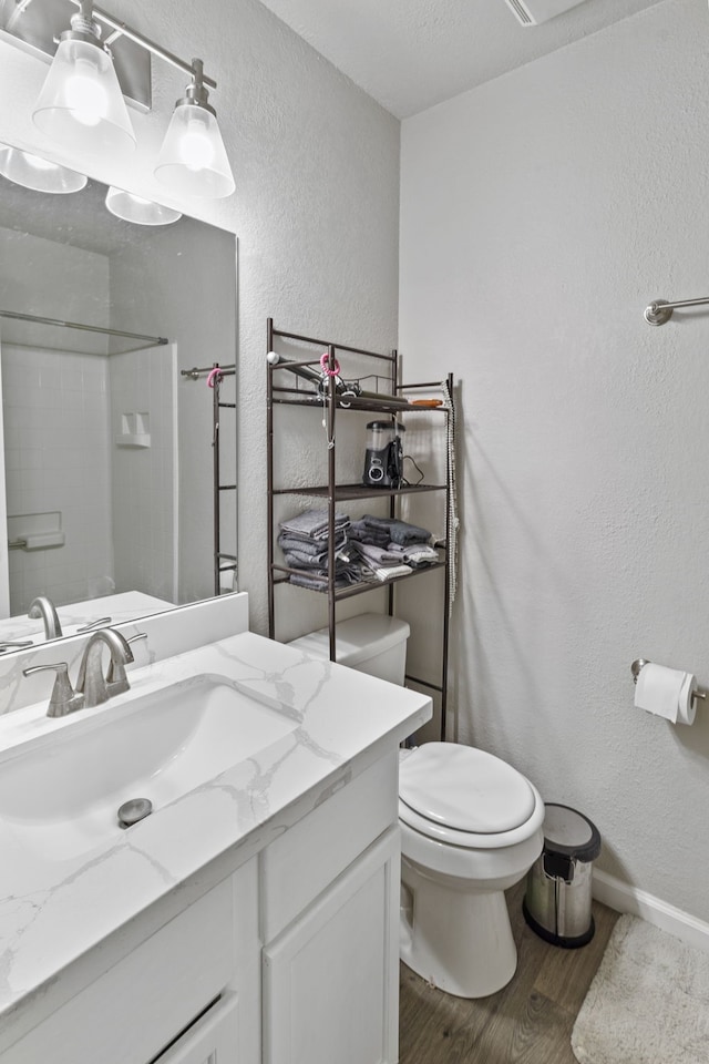 bathroom featuring toilet, vanity, wood-type flooring, and walk in shower