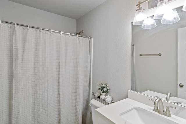 bathroom with walk in shower, vanity, and toilet