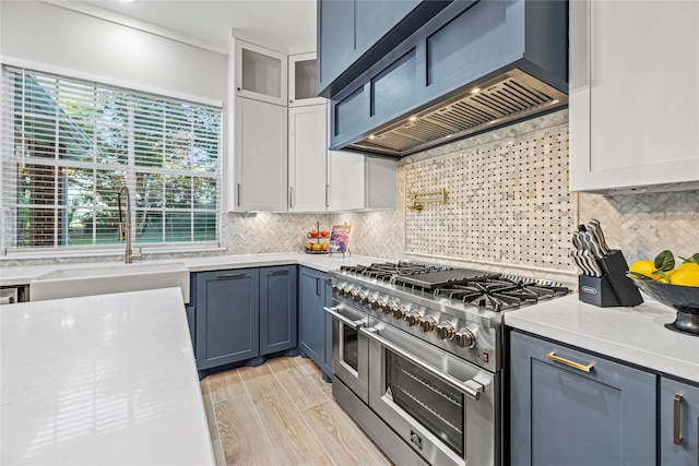 kitchen with sink, white cabinetry, custom range hood, light hardwood / wood-style floors, and range with two ovens