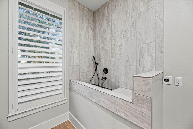 bathroom with a tile shower and wood-type flooring