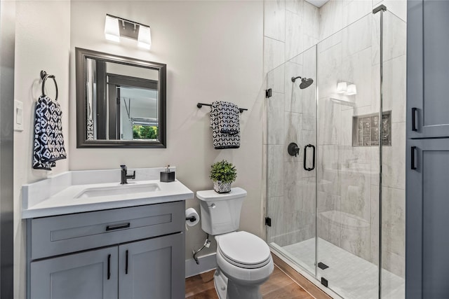 bathroom featuring vanity, toilet, a shower with shower door, and wood-type flooring