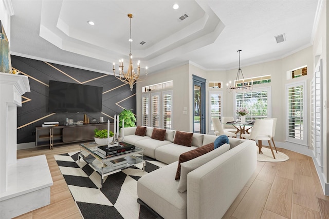 living room with a notable chandelier, a tray ceiling, and crown molding