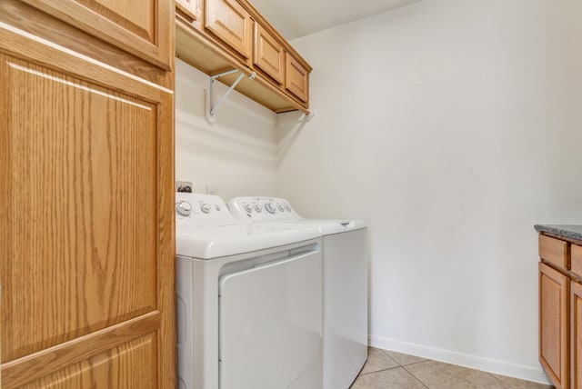 laundry area featuring washer and dryer, light tile patterned floors, and cabinets