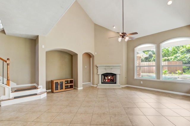 unfurnished living room with light tile patterned floors, high vaulted ceiling, and ceiling fan