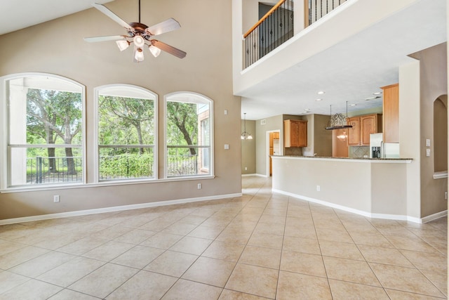 unfurnished living room with ceiling fan, light tile patterned floors, and high vaulted ceiling