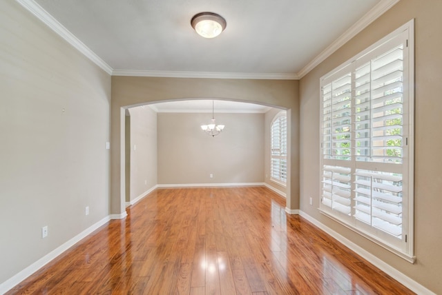 empty room featuring crown molding, light hardwood / wood-style floors, and an inviting chandelier