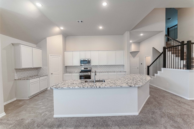 kitchen featuring an island with sink, stainless steel appliances, sink, and white cabinetry