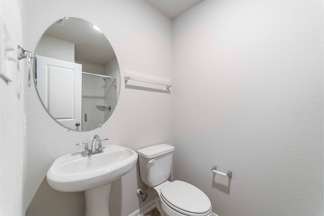 bathroom with toilet, sink, and a shower with shower door