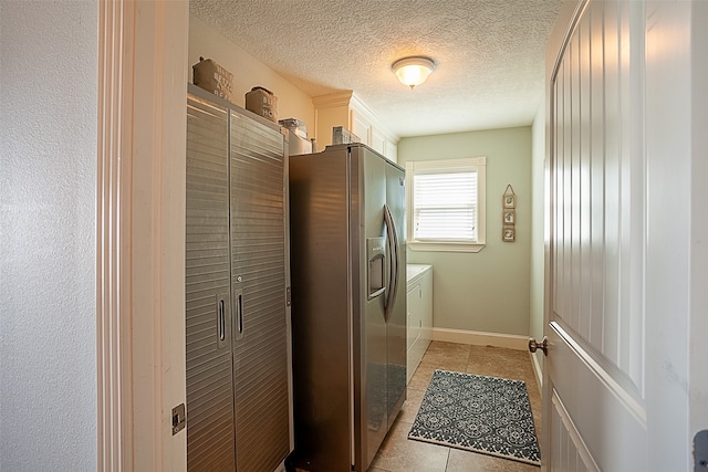 laundry room featuring light tile patterned flooring, separate washer and dryer, and a textured ceiling