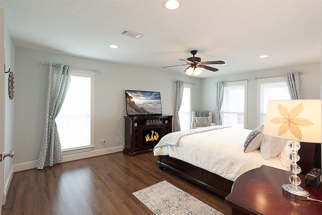 bedroom with ceiling fan, dark hardwood / wood-style floors, and a textured ceiling