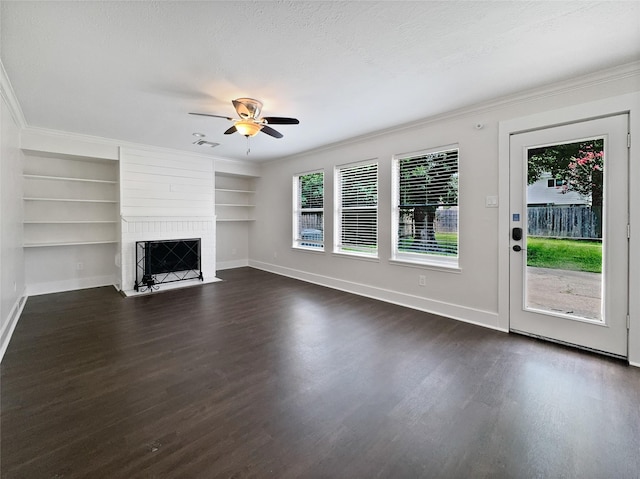 unfurnished living room featuring a textured ceiling, built in shelves, a brick fireplace, ornamental molding, and ceiling fan