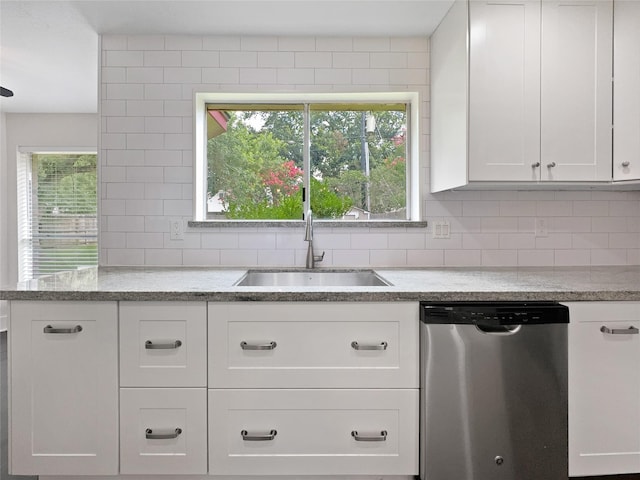 kitchen featuring stainless steel dishwasher, white cabinetry, sink, and backsplash