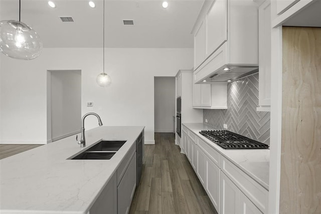 kitchen with stainless steel gas stovetop, sink, dark wood-type flooring, pendant lighting, and tasteful backsplash