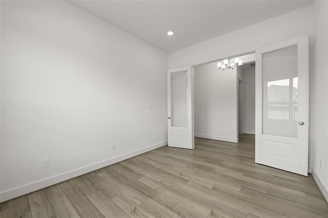 unfurnished bedroom with hardwood / wood-style floors and a notable chandelier