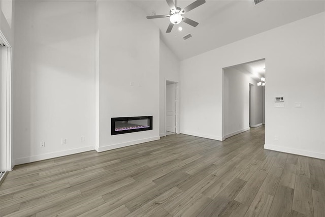 unfurnished living room featuring ceiling fan with notable chandelier, high vaulted ceiling, and wood-type flooring