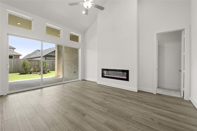 unfurnished living room with high vaulted ceiling, wood-type flooring, a wealth of natural light, and ceiling fan