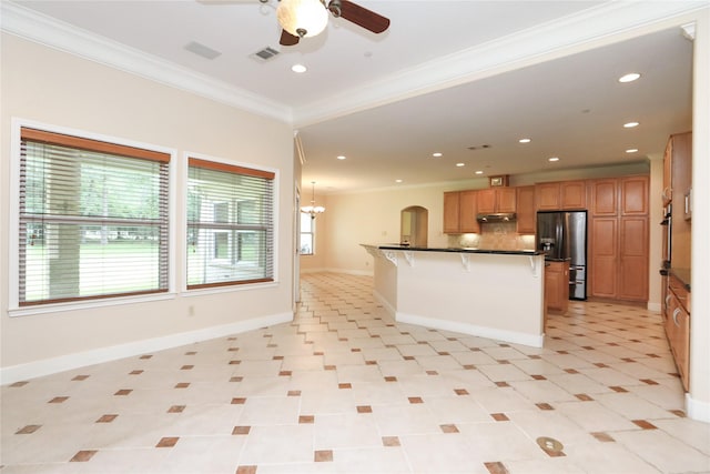 kitchen featuring a center island, ornamental molding, tasteful backsplash, stainless steel fridge with ice dispenser, and a breakfast bar area