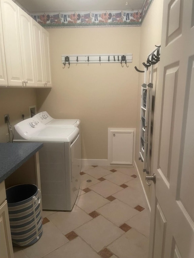 clothes washing area featuring washer and dryer, cabinets, and light tile patterned floors