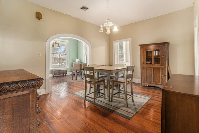 dining room featuring a chandelier, a healthy amount of sunlight, and dark hardwood / wood-style floors