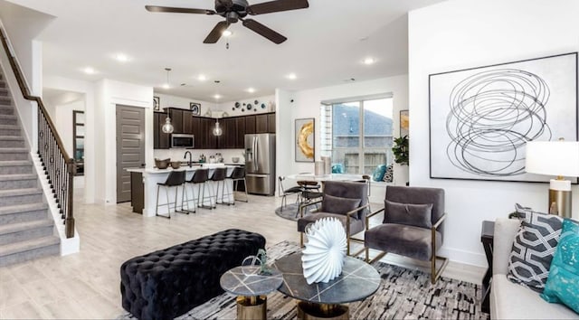 living room featuring sink, light wood-type flooring, and ceiling fan