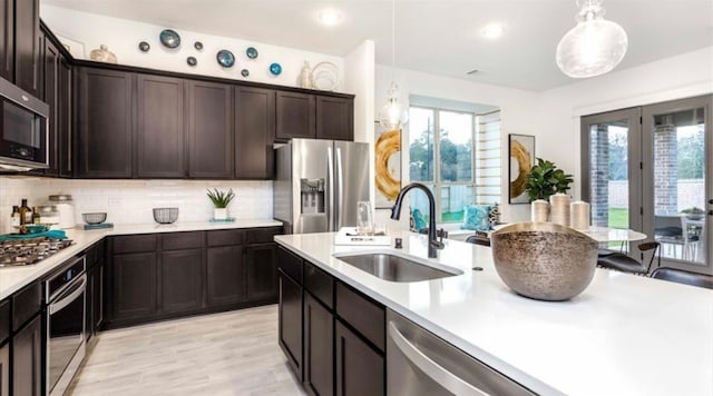 kitchen featuring decorative light fixtures, dark brown cabinetry, stainless steel appliances, backsplash, and sink