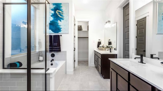 bathroom featuring tile floors, tiled tub, and double vanity