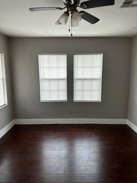 empty room with dark hardwood / wood-style flooring and ceiling fan