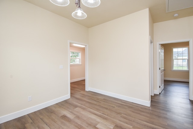 unfurnished room featuring plenty of natural light, light wood-type flooring, and a chandelier