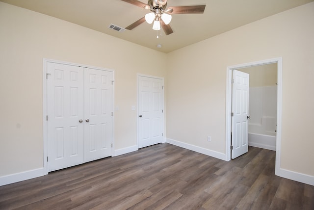 unfurnished bedroom with connected bathroom, dark hardwood / wood-style floors, and ceiling fan