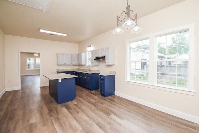 kitchen featuring sink, decorative light fixtures, white cabinets, a center island, and plenty of natural light