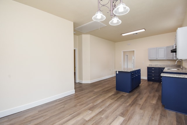 kitchen featuring a center island, sink, hanging light fixtures, white cabinetry, and wood-type flooring