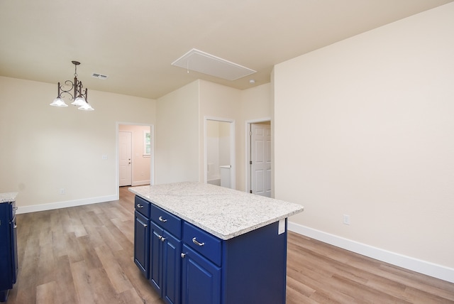 kitchen featuring an inviting chandelier, blue cabinets, decorative light fixtures, a kitchen island, and light wood-type flooring