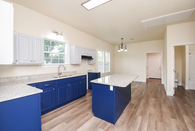 kitchen featuring white cabinetry, sink, hanging light fixtures, light hardwood / wood-style floors, and a kitchen island