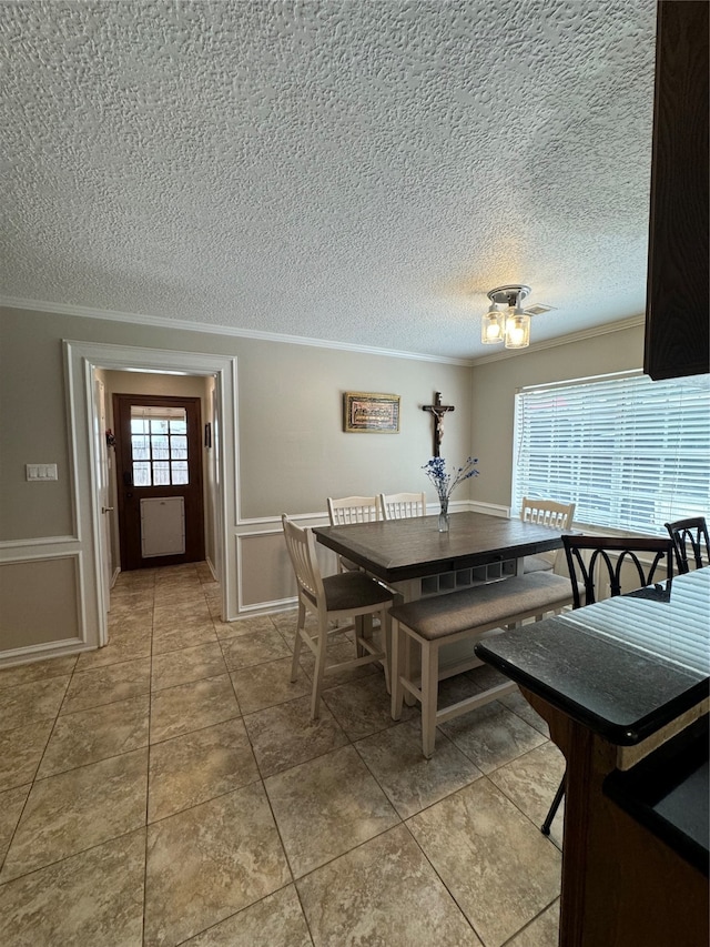 dining space with a textured ceiling, ornamental molding, and tile patterned floors