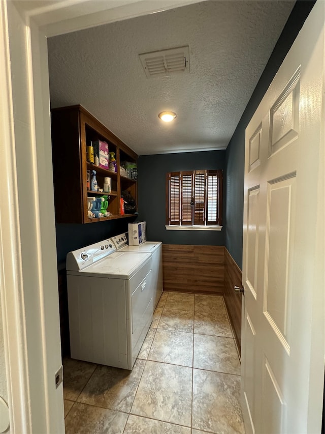 laundry area with a textured ceiling, light tile patterned flooring, and separate washer and dryer