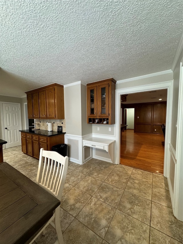 kitchen with hardwood / wood-style floors, backsplash, crown molding, and a textured ceiling