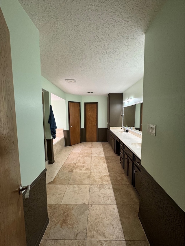 bathroom with double sink vanity, a textured ceiling, and tile patterned floors