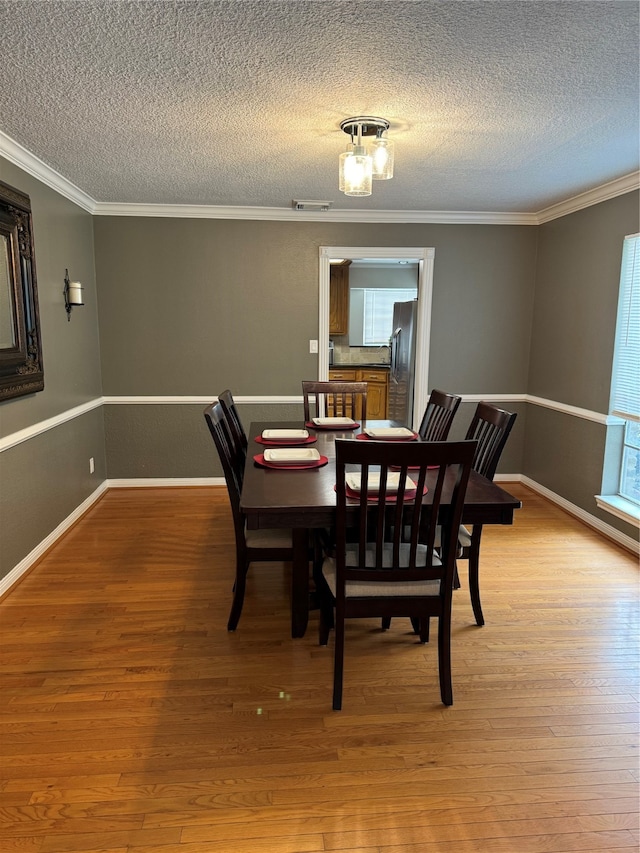 dining room featuring a textured ceiling, crown molding, and hardwood / wood-style floors